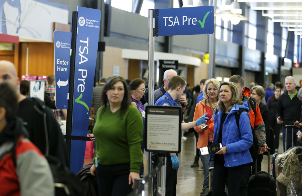 In this March 17, 2016, photo, travelers authorized to use the TSA PreCheck expedited security line at Seattle-Tacoma International Airport in Seattle have their documents checked by Transportation Security Administration workers. Fliers will likely face massive security lines at airports across the country this summer, with airlines already warning passengers to arrive at least two hours early or risk missing their flight. (AP Photo/Ted S. Warren)